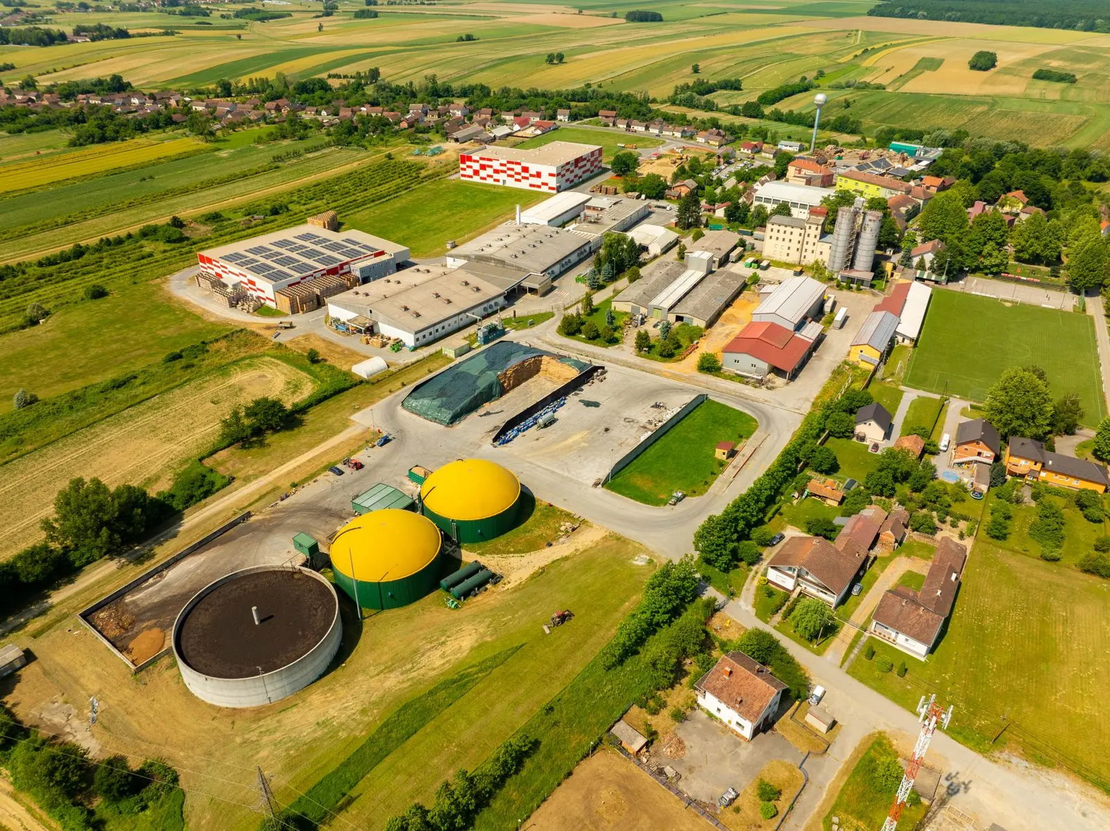 Aerial view of a biogas plant with green digester tanks among farmland