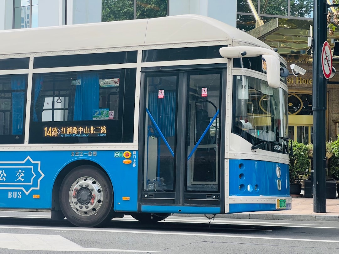 A blue and white city bus at a kerbside stop