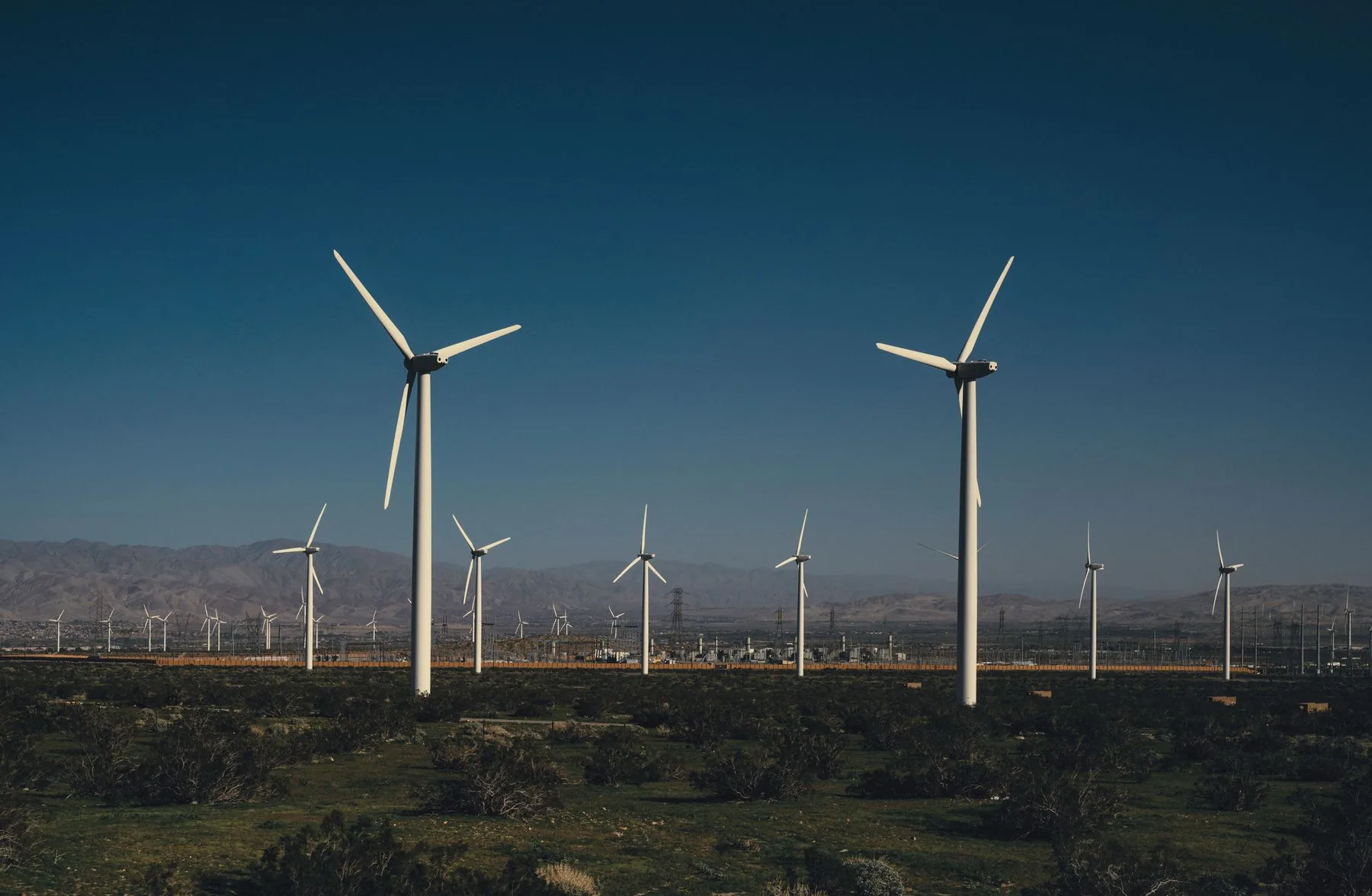 A field of onshore wind turbines under a clear blue sky